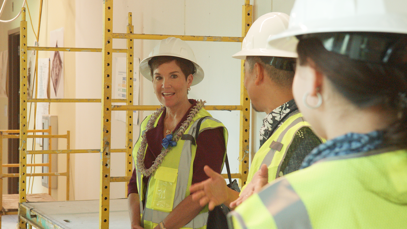 UH President Wendy Hensel smiling and listening to a researcher